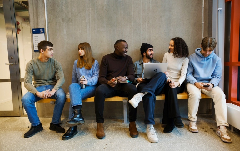 En grupp studenter sitter på en bänk.